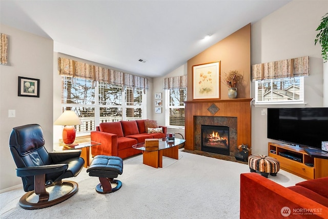 living area with lofted ceiling, visible vents, a tiled fireplace, and carpet flooring