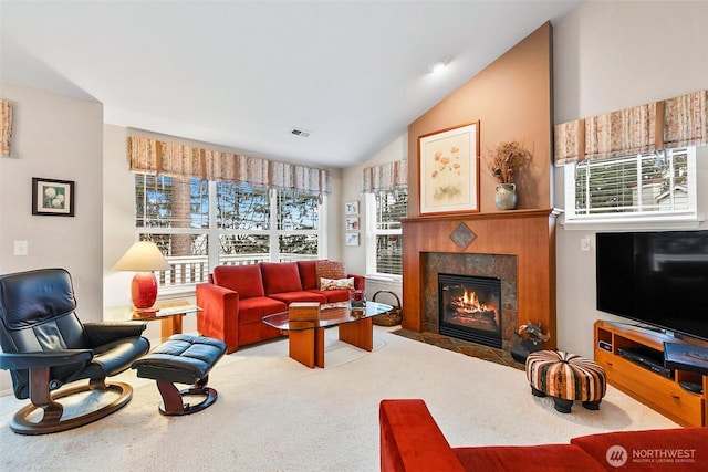 carpeted living area with lofted ceiling, visible vents, plenty of natural light, and a premium fireplace