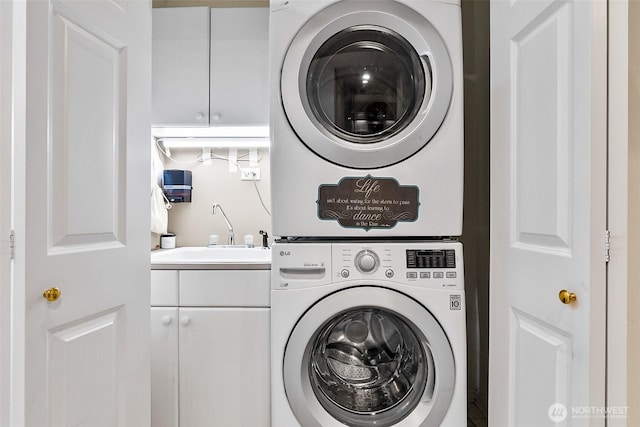 laundry area with stacked washer / drying machine, cabinet space, and a sink