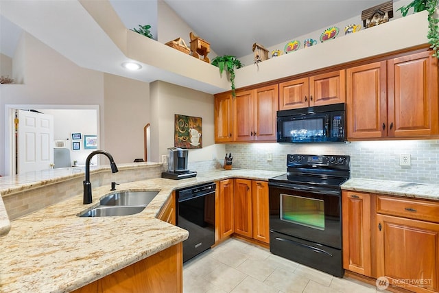 kitchen with a sink, light stone countertops, black appliances, tasteful backsplash, and brown cabinetry