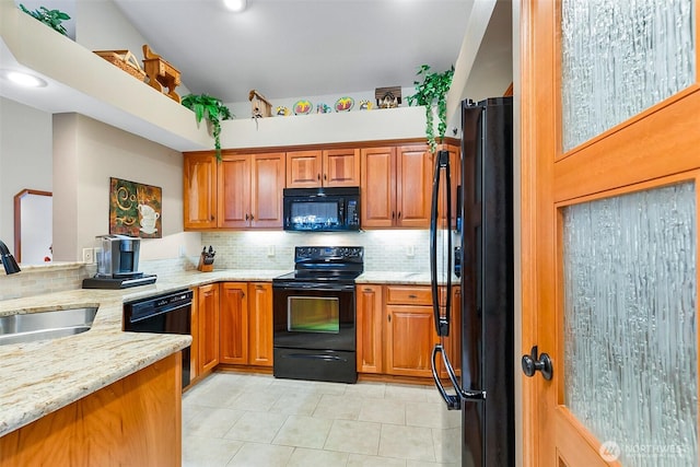 kitchen with black appliances, light stone counters, brown cabinetry, and a sink