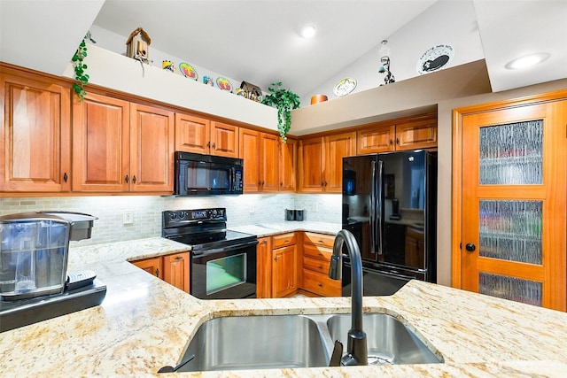 kitchen with light stone countertops, black appliances, brown cabinets, and a sink