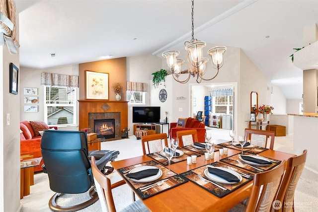 dining space with light colored carpet, visible vents, a fireplace with flush hearth, vaulted ceiling, and a chandelier