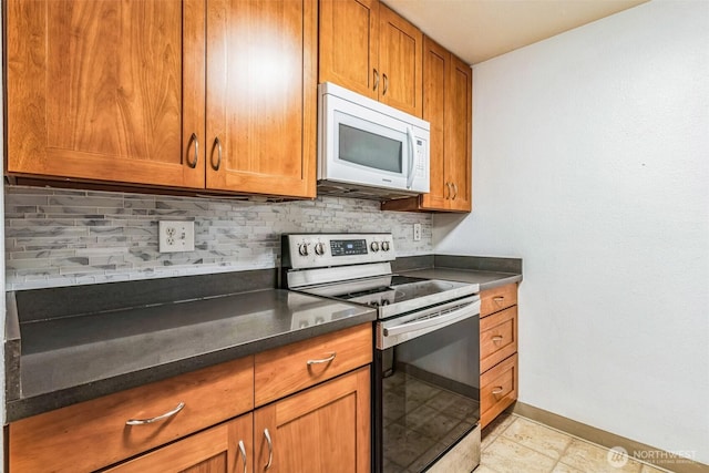 kitchen featuring electric stove, white microwave, brown cabinetry, and dark countertops