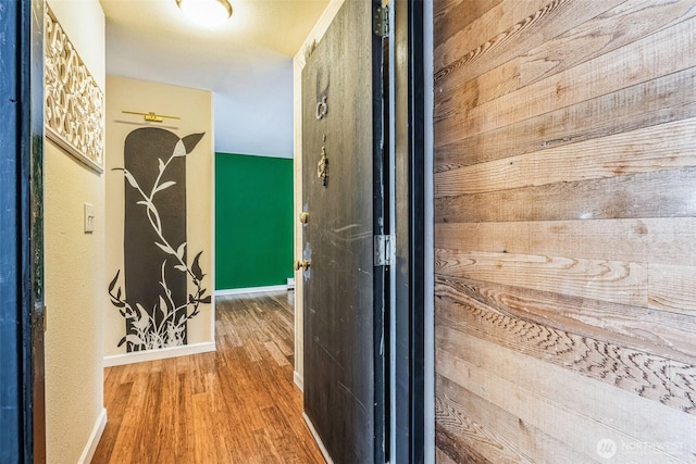 corridor with baseboards and wood finished floors