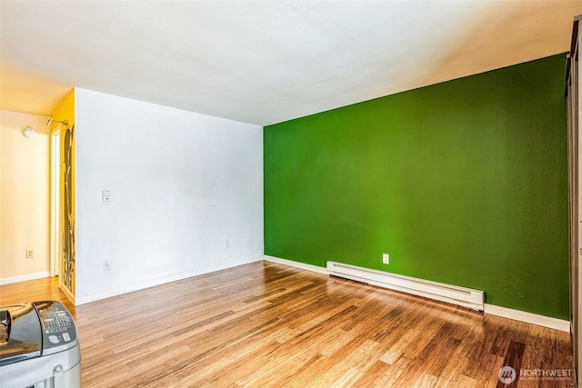 unfurnished room with a baseboard radiator, baseboards, and light wood finished floors