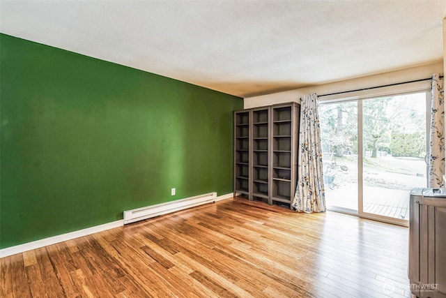 spare room featuring light wood-style flooring, baseboards, and baseboard heating