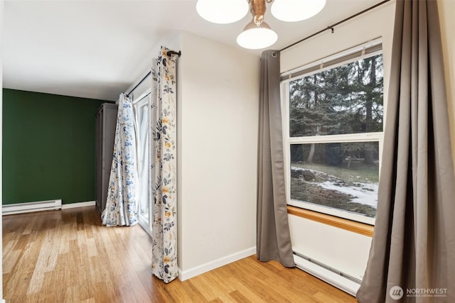 interior space featuring a baseboard radiator, light wood-style flooring, and baseboards