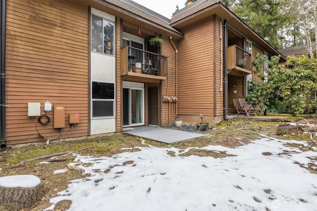 snow covered house featuring a patio