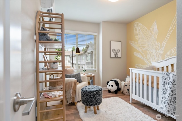 bedroom with a crib, baseboards, and wood finished floors