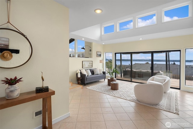 living room with visible vents, baseboards, a high ceiling, light tile patterned flooring, and recessed lighting