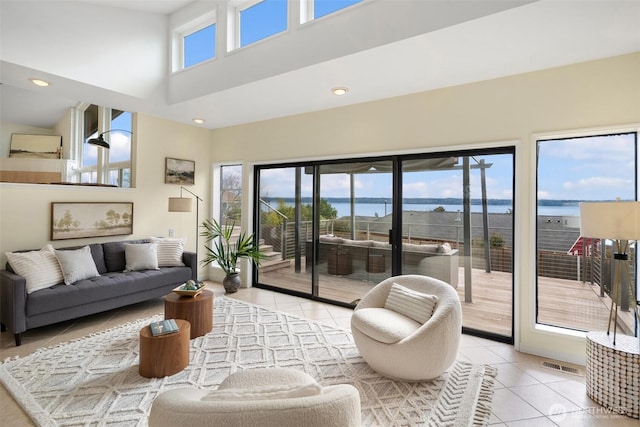 living room featuring light tile patterned flooring, recessed lighting, visible vents, and a towering ceiling