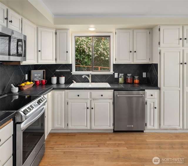 kitchen featuring white cabinets, light wood-style floors, appliances with stainless steel finishes, and a sink