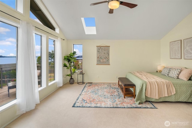 bedroom featuring access to outside, vaulted ceiling with skylight, carpet flooring, and ceiling fan