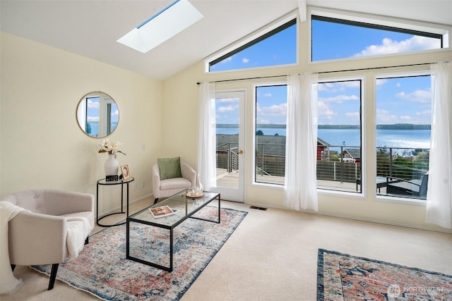 interior space featuring lofted ceiling with skylight, carpet, a water view, and visible vents