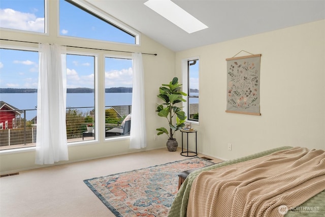 bedroom featuring baseboards, visible vents, vaulted ceiling with skylight, a water view, and carpet flooring