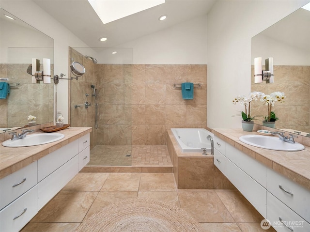 bathroom with vaulted ceiling with skylight, a garden tub, walk in shower, and a sink