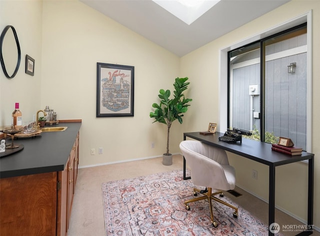 home office with a sink, baseboards, lofted ceiling with skylight, and carpet