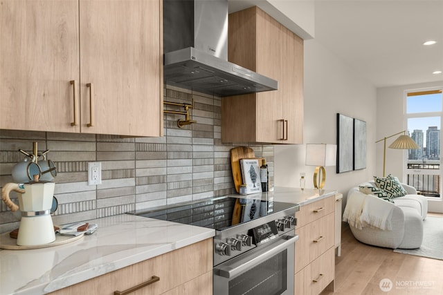 kitchen featuring light brown cabinets, wall chimney range hood, stainless steel electric range, light stone countertops, and modern cabinets