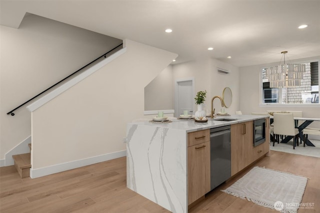 kitchen with dishwasher, light wood-style flooring, a kitchen island with sink, black microwave, and a sink