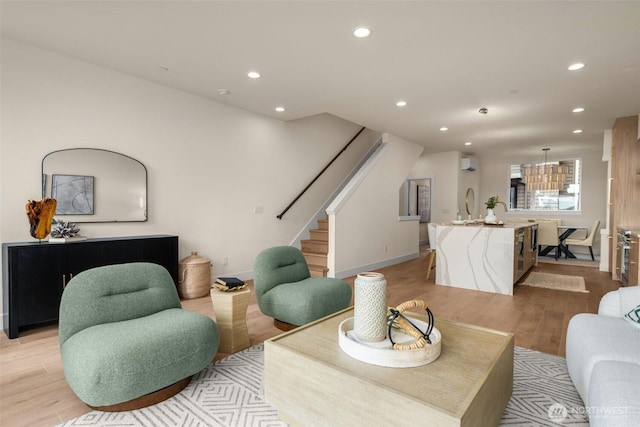 living area featuring light wood finished floors, stairway, a wall unit AC, and recessed lighting