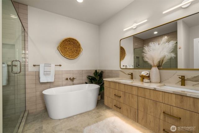 full bathroom featuring a freestanding bath, double vanity, a stall shower, and a sink