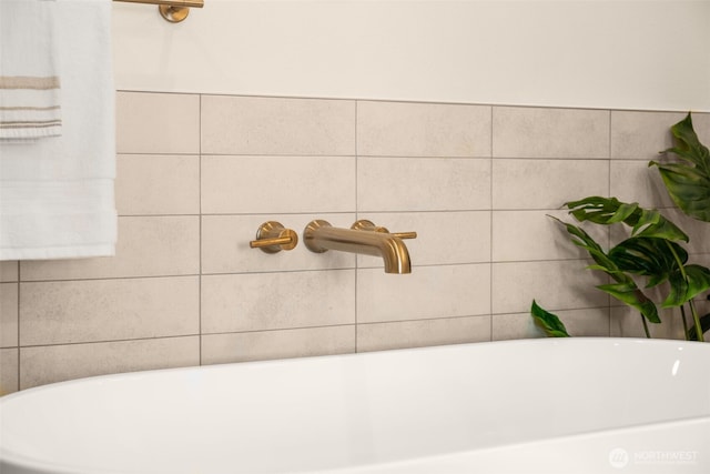 bathroom featuring a soaking tub, a sink, and tile walls