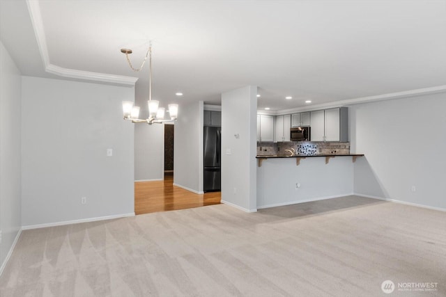 unfurnished living room with recessed lighting, baseboards, light carpet, and a notable chandelier