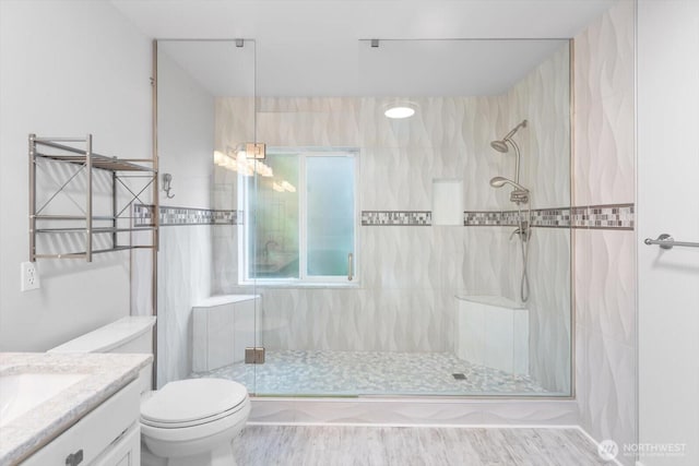 bathroom featuring toilet, vanity, and a tile shower