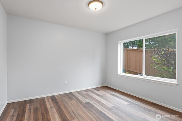 spare room featuring baseboards and wood finished floors