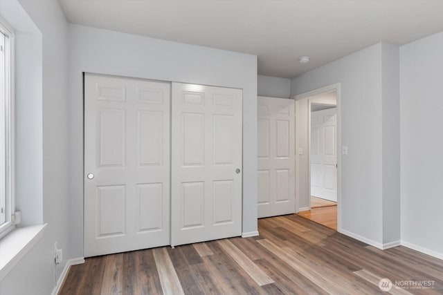 unfurnished bedroom with a closet, baseboards, and wood finished floors