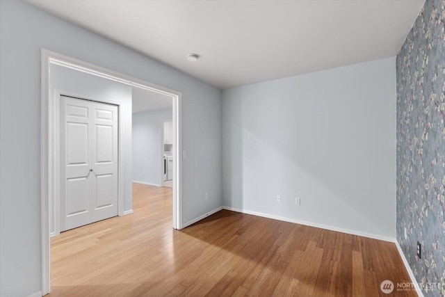 empty room featuring washer / dryer, baseboards, and wood finished floors