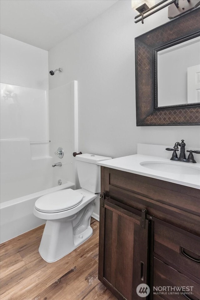 bathroom featuring shower / bath combination, toilet, vanity, and wood finished floors