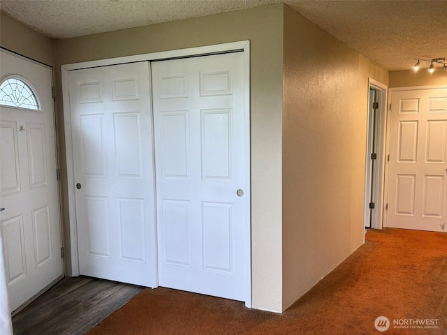 interior space featuring dark carpet and a textured ceiling