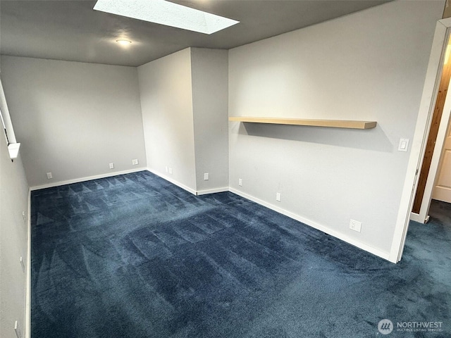 empty room featuring a skylight, baseboards, and dark carpet