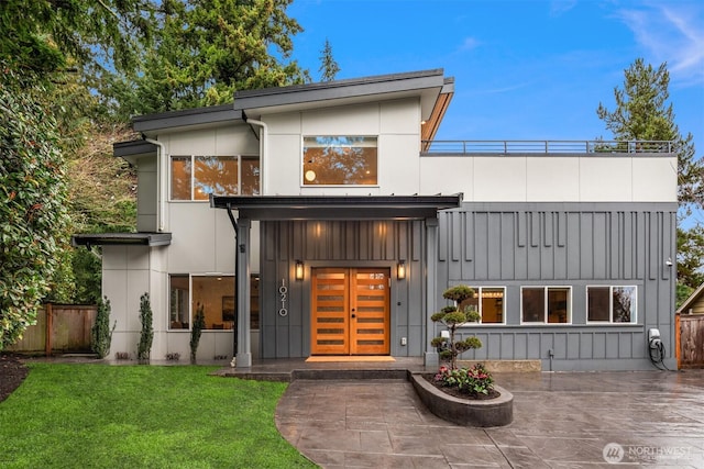 exterior space with french doors, board and batten siding, fence, and a lawn