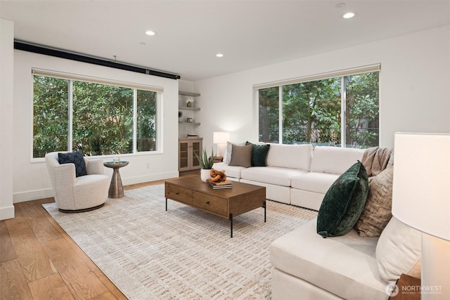 living area with baseboards, light wood-style flooring, and recessed lighting