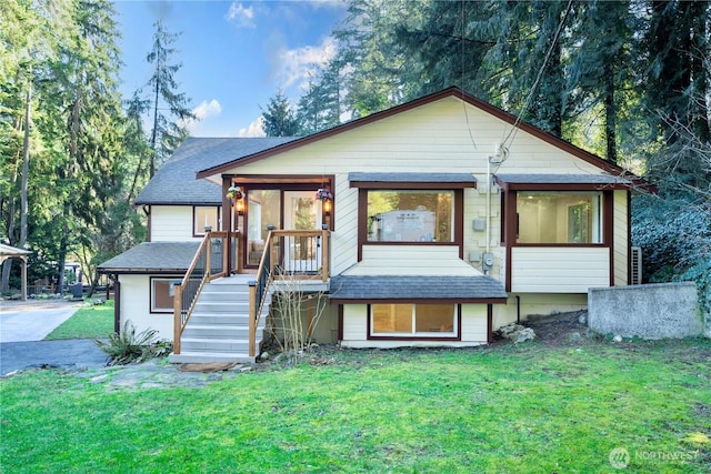 view of front of home with stairs, a shingled roof, and a front yard