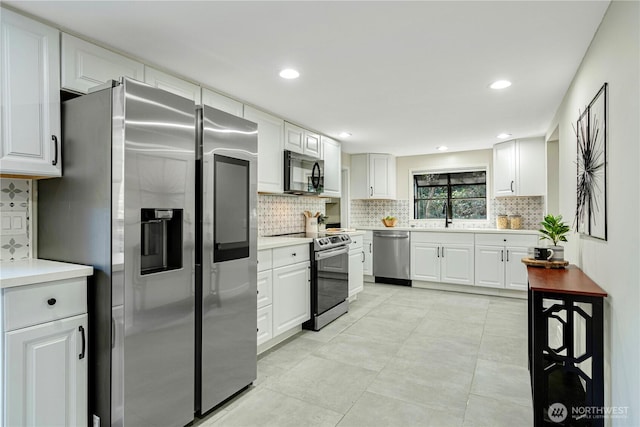 kitchen with appliances with stainless steel finishes, light countertops, a sink, and white cabinetry