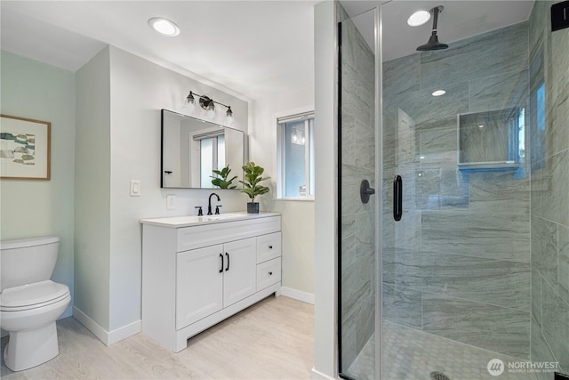 full bathroom featuring a stall shower, vanity, toilet, and baseboards