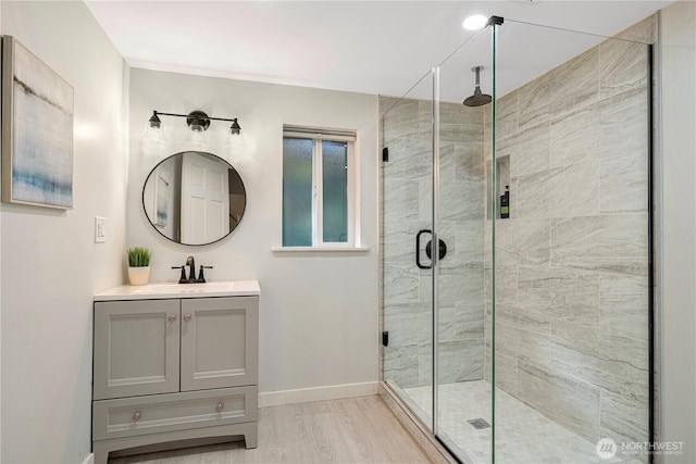 full bath featuring a shower stall, baseboards, wood finished floors, and vanity