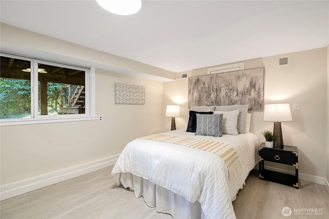 bedroom featuring light wood-type flooring, visible vents, and baseboards