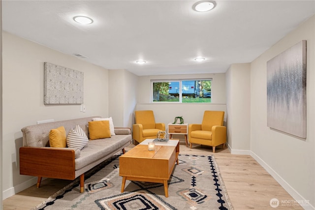 living area with baseboards, visible vents, and light wood-style floors