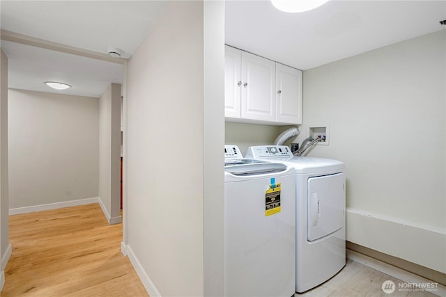 clothes washing area with light wood finished floors, washer and clothes dryer, cabinet space, and baseboards