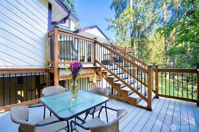 wooden terrace with outdoor dining space and stairway