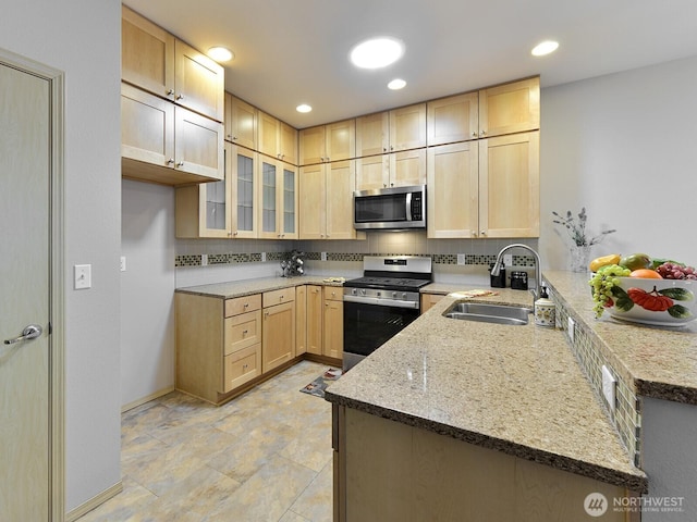 kitchen with a peninsula, a sink, appliances with stainless steel finishes, decorative backsplash, and light brown cabinetry