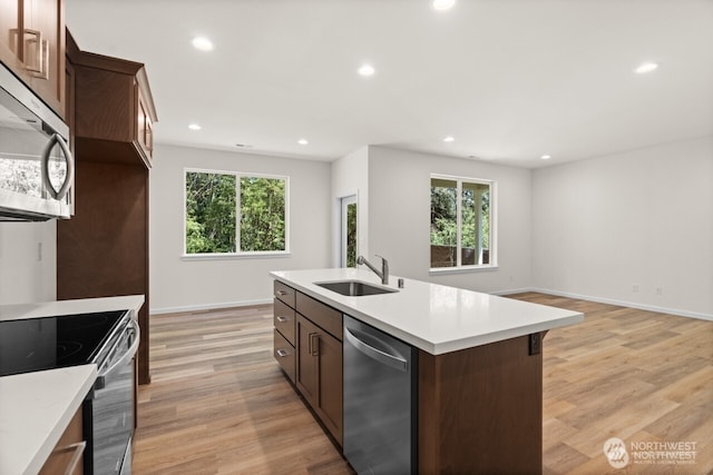 kitchen with light wood-style flooring, stainless steel appliances, a sink, and recessed lighting