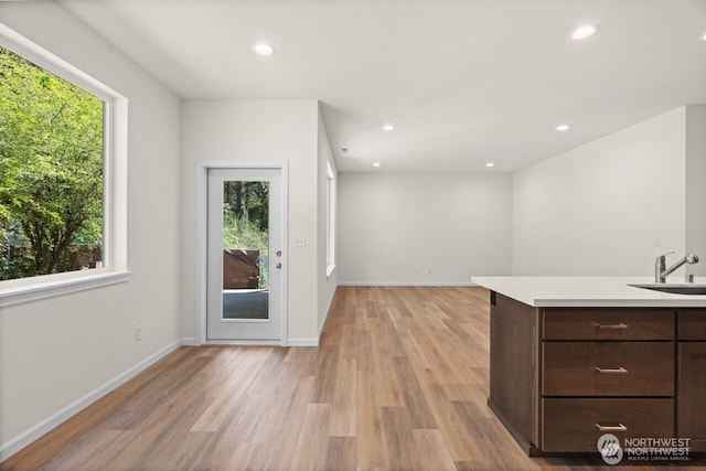 interior space featuring light wood-type flooring, a sink, baseboards, and recessed lighting