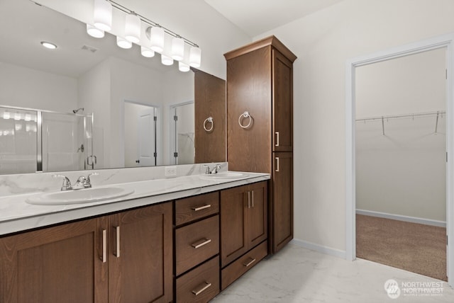 bathroom featuring marble finish floor, a sink, a shower stall, and baseboards