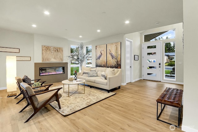 living area featuring light wood-type flooring, a fireplace, baseboards, and recessed lighting